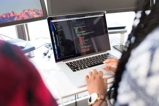 pexels-photo-1181467-1181467 A woman coding on a laptop in a modern office environment with multiple monitors.