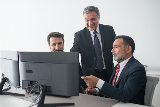 pexels-photo-8353834-8353834 Three business colleagues in suits happily collaborating at the office.